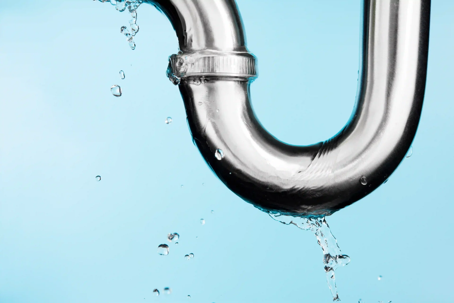 Hands using pliers to tighten a valve on copper plumbing pipes beside a residential water heater system.